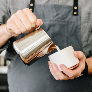 Barista naleje mlieko z leštenej kanvice z nehrdzavejúcej ocele, súčasť Espresso príslušenstva a mliečnej kanvice, všetko o káve.