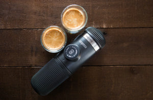 Prenosný espresso stroj s dvoma šálkami espressa na drevenom povrchu, z prenosných kávovarov a baristického vybavenia
